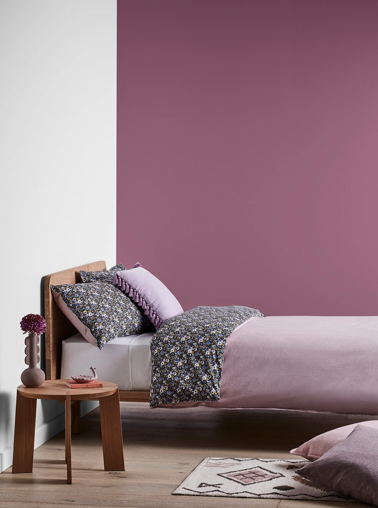 Purple bedroom with timber bed and side table and purple linens.
