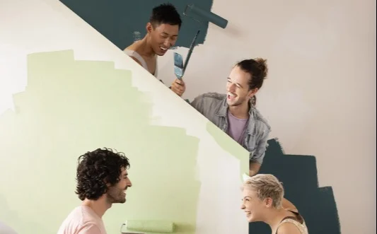 people painting staircase with rollers and green paint