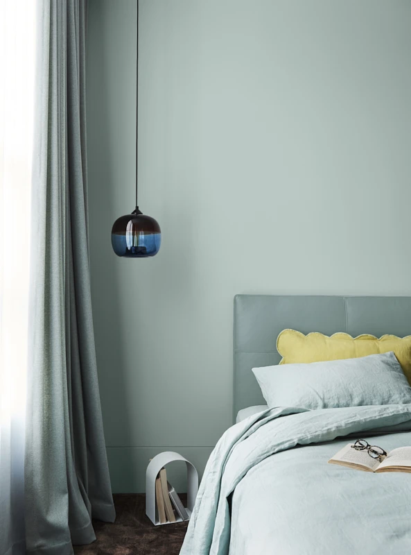Bed in front of green wall with hanging light