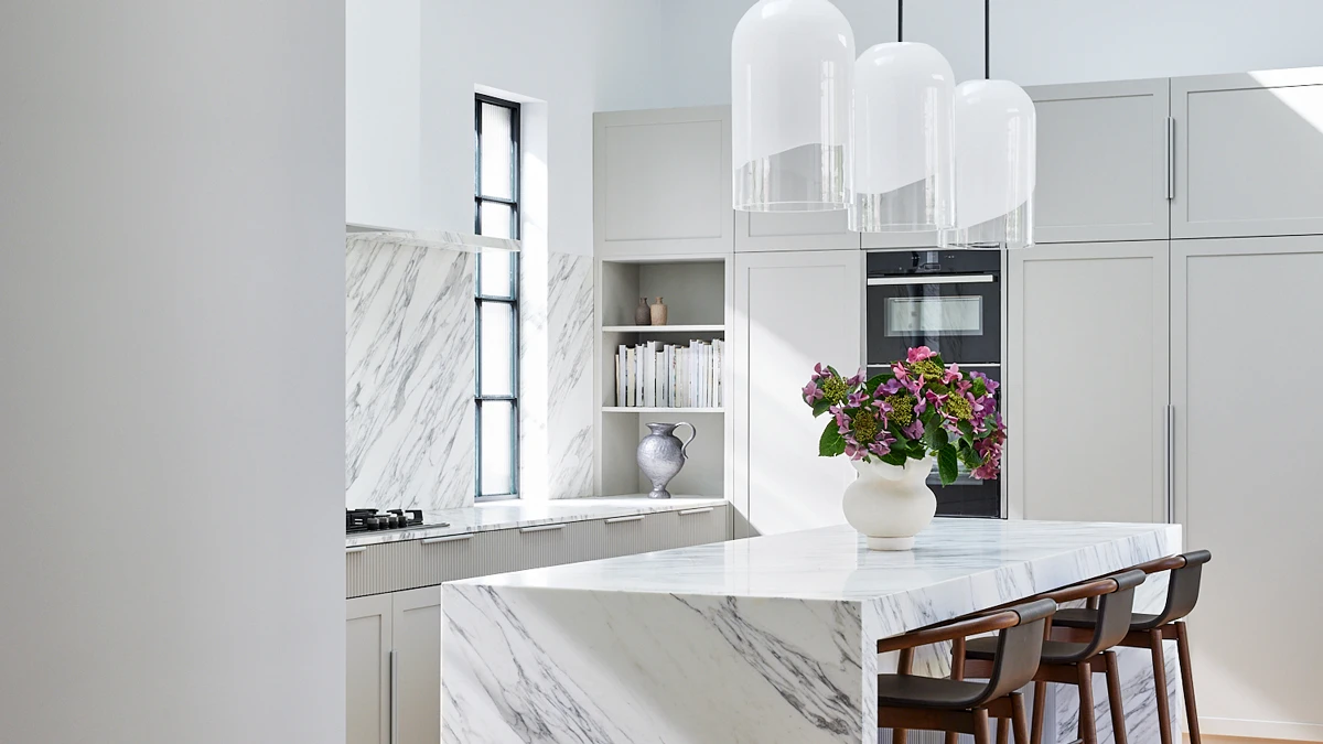 Marble benches and splashbacks in kitchen against cream cabinetry. 