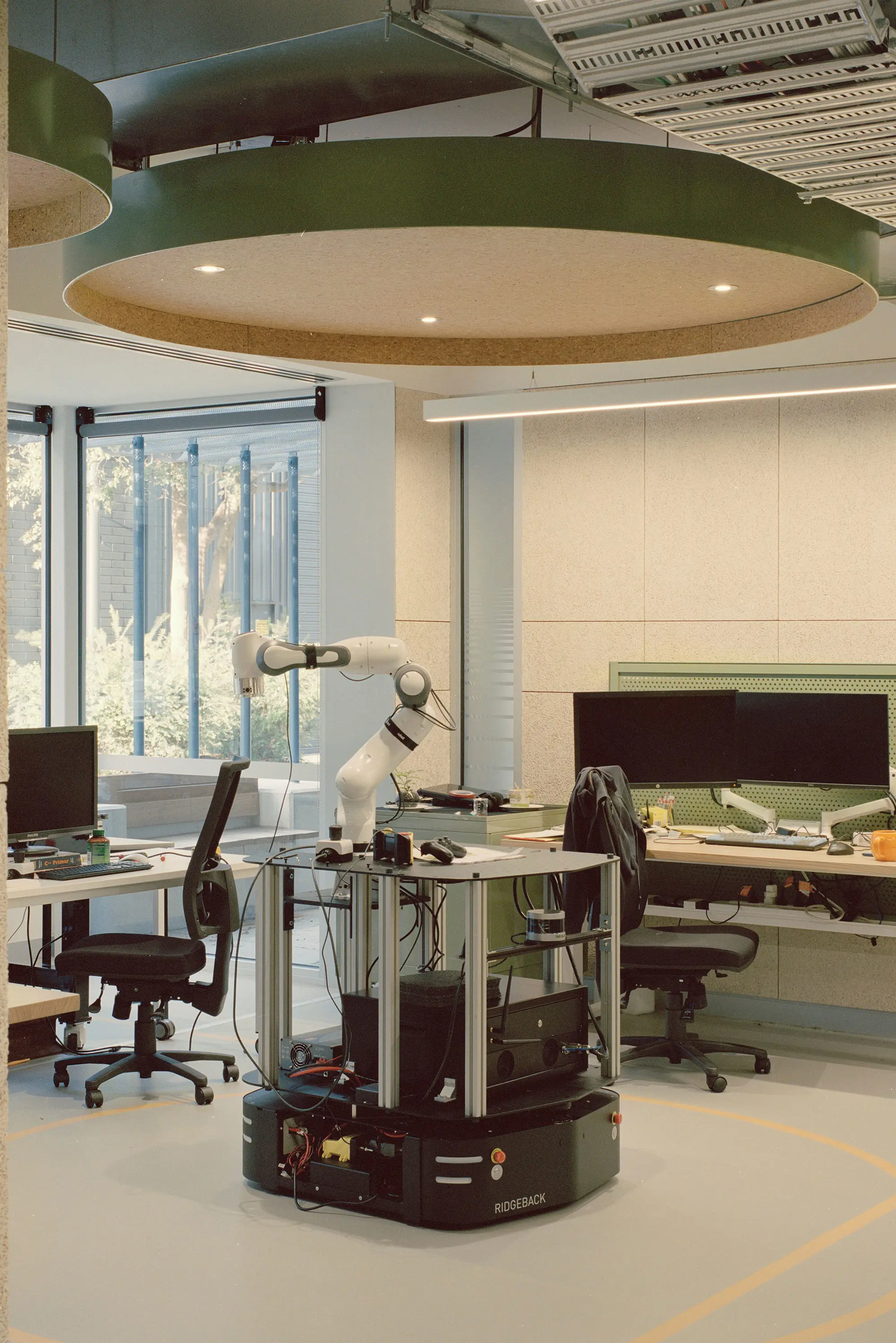 Green and white office with robotic arm on desk.