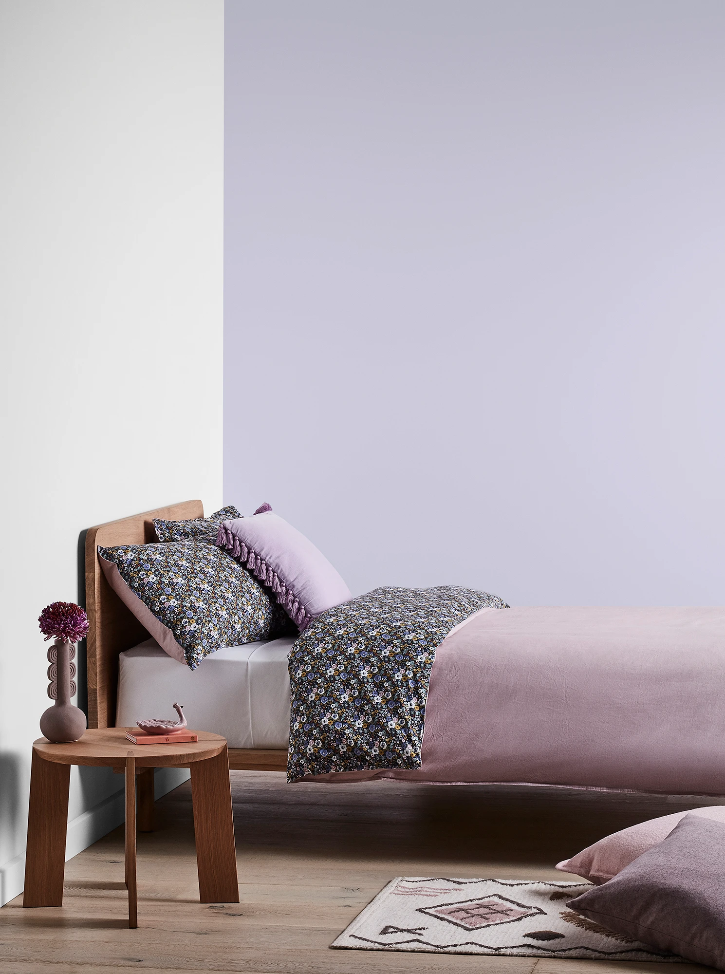 Purple bedroom with timber bed and side table and purple linens.