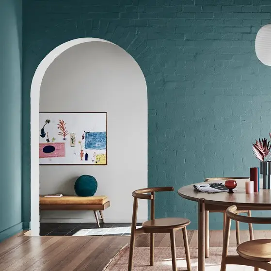 Green dining room with archway, wooden table and chairs, and timber floors.