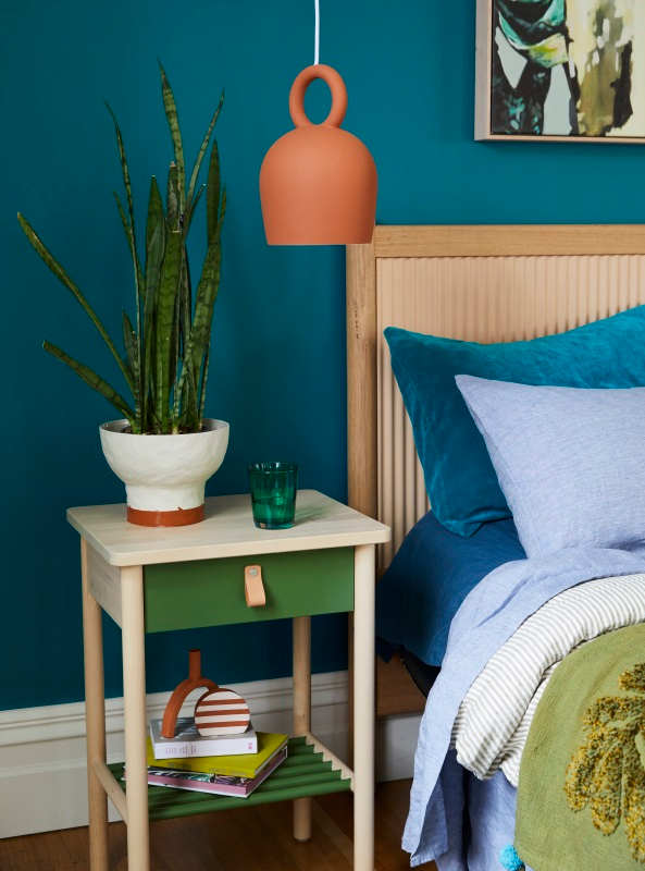 A green side table in a bedroom