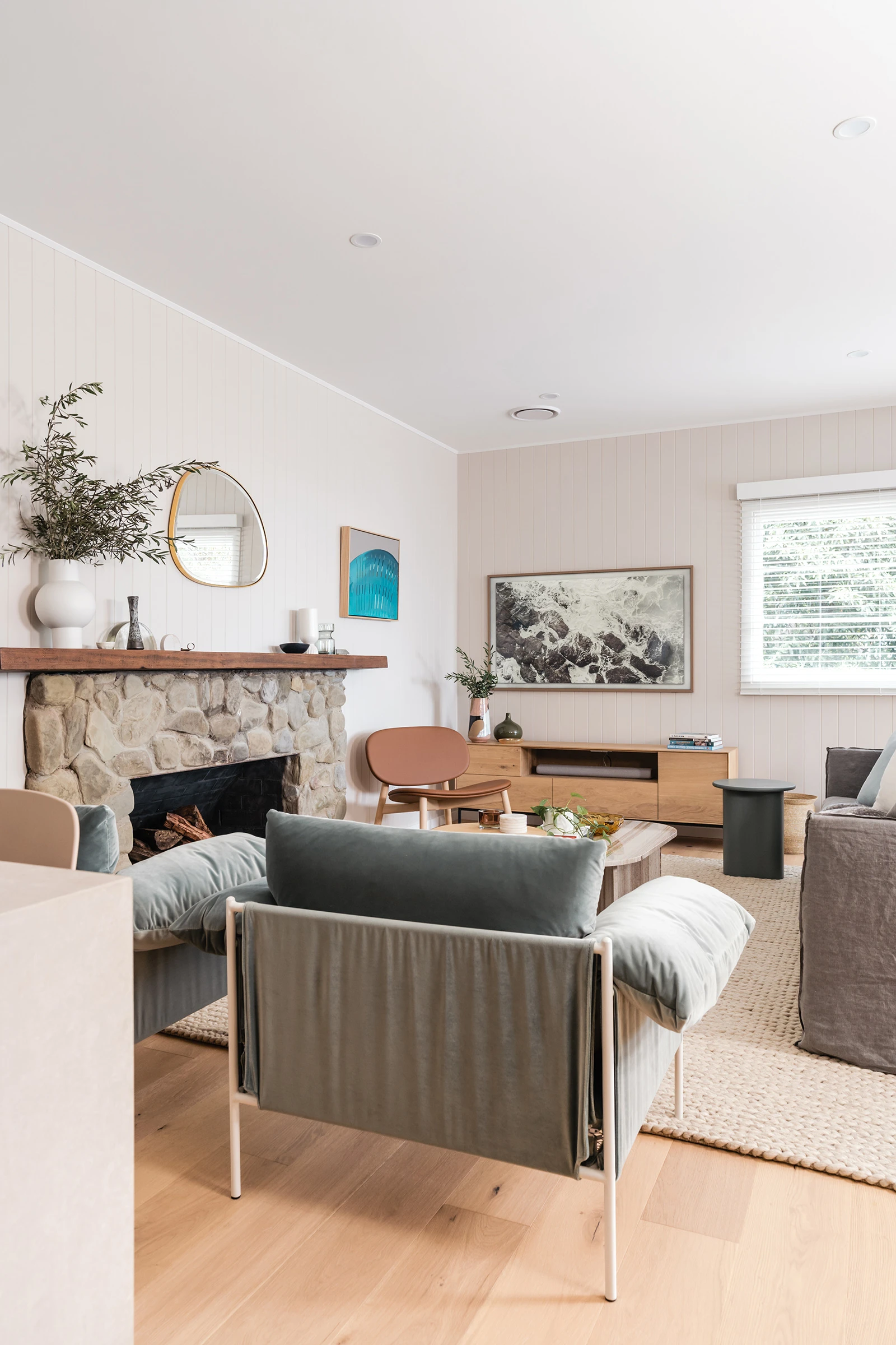 A relaxed living room with a large stone fireplace and timber mantle