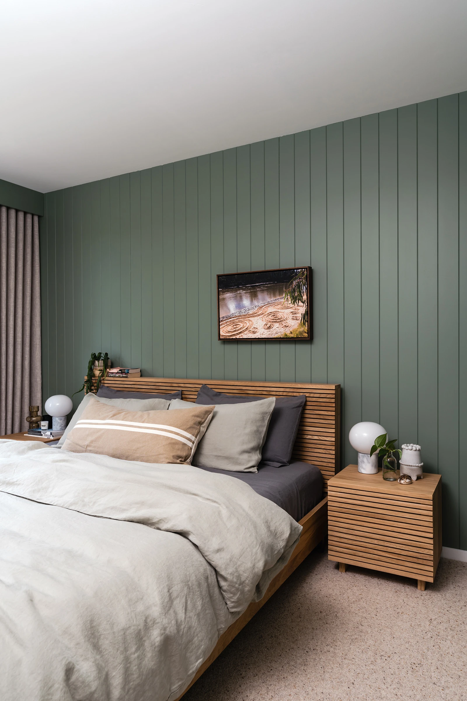 Green guest bedroom with timber bedframe and bedside table