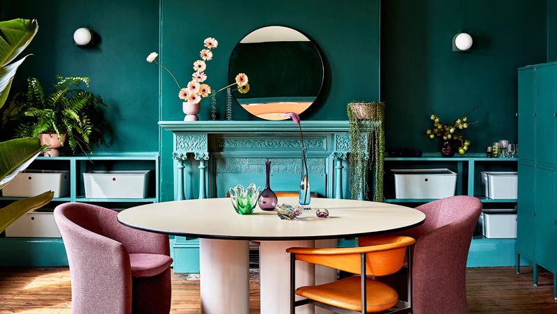 Teal room with traditional mantle, round table with pink chairs