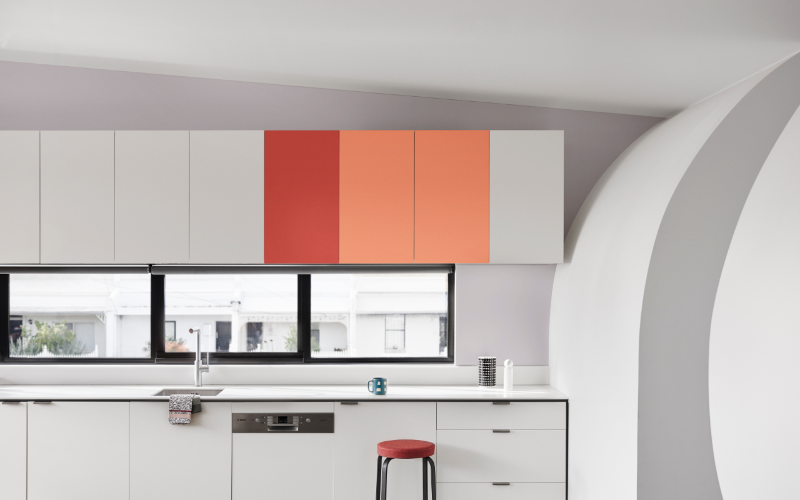 White and grey kitchen with orange and red cupboards in Dulux Eskimo White, Capital Red, Baby Melon, and Lexicon® Quarter.