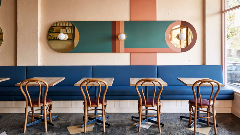 interior dining setting with blue bench seats and green and orange wall decor.