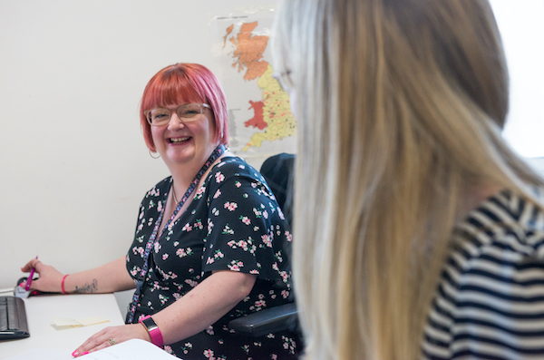 Woman sitting at desk laughing with a colleague