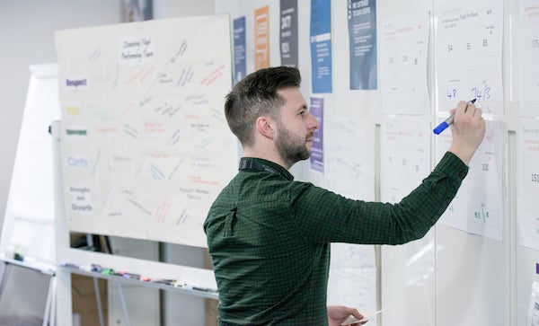 Man writing on a printout on a wall