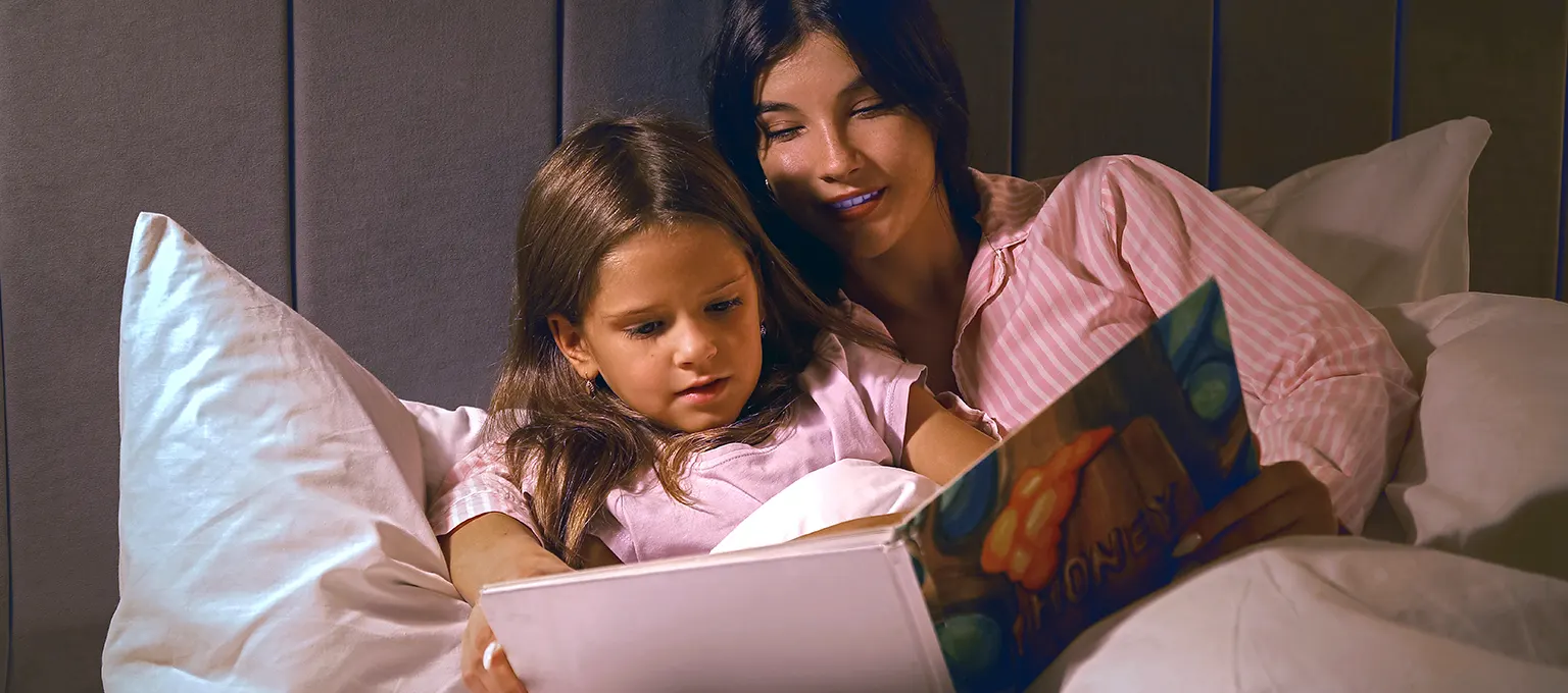 Mamá leyendo un libro con su hija en cama 