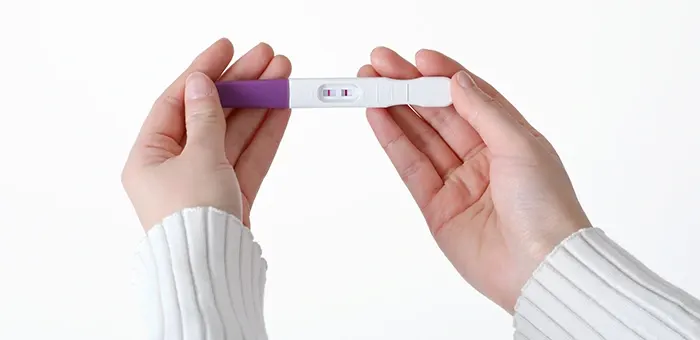 Mujer con primeros síntomas de embarazo viendo prueba de embarazo