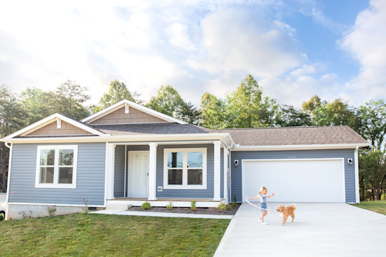 Young girl plays with her dog in front of her Clayton Built CrossMod home