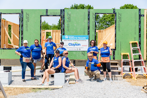Group of women volunteers posing in front of Habitat for Humanity build site