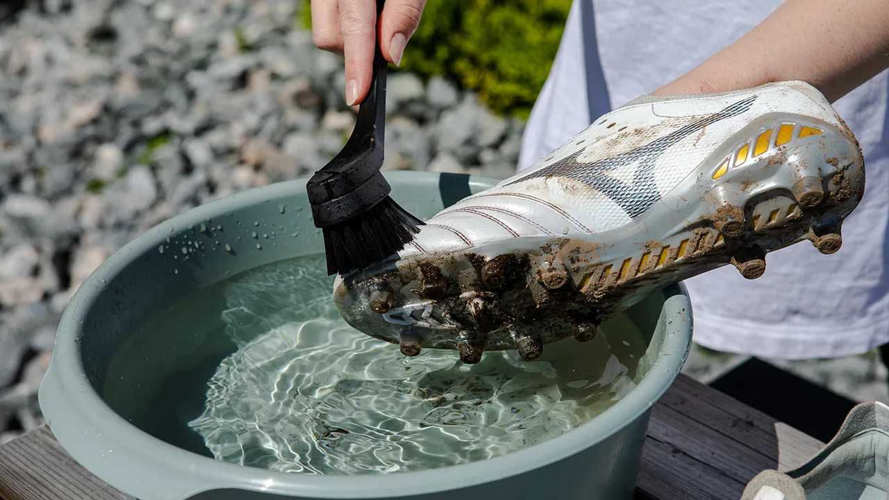 Fotballsko kan rengjøres med en oppvaskbørste