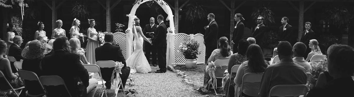 A bride and groom stand before the alter while the wedding party and guests look on.