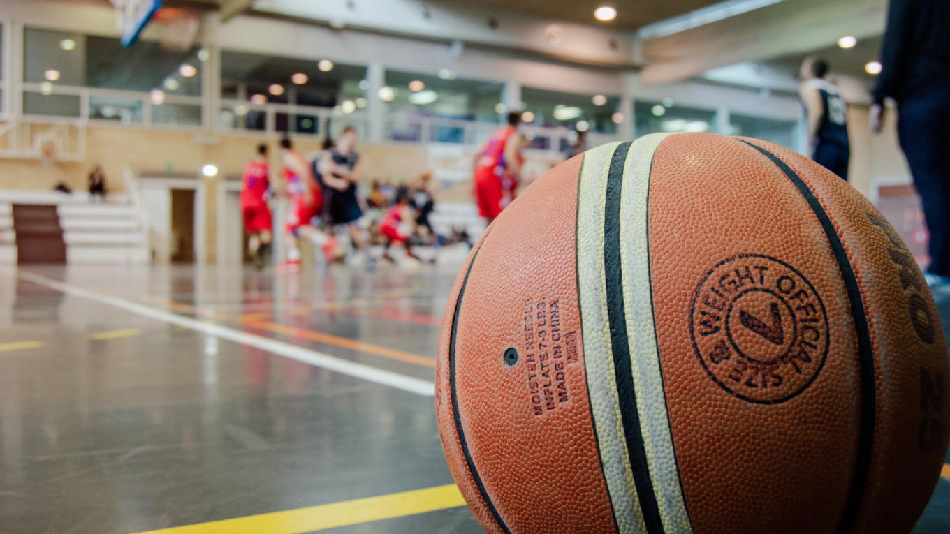 A basketball resting on the sidelines of the court during a game.