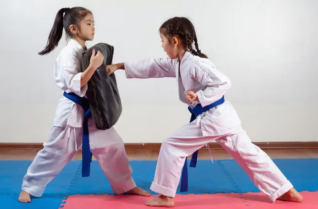 Two girls training martial arts wearing a gi and blue belt 