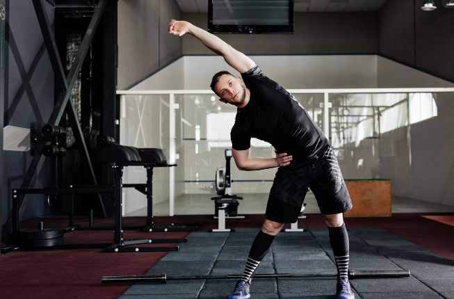 man warming up for martial arts class in a gym stretching 