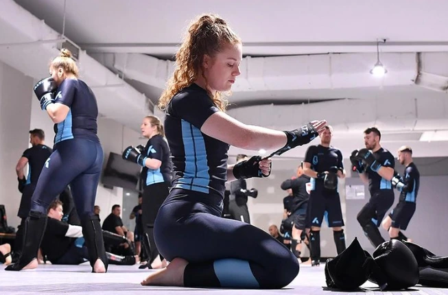 Women wrapping wrist for martial arts training at Alta gym