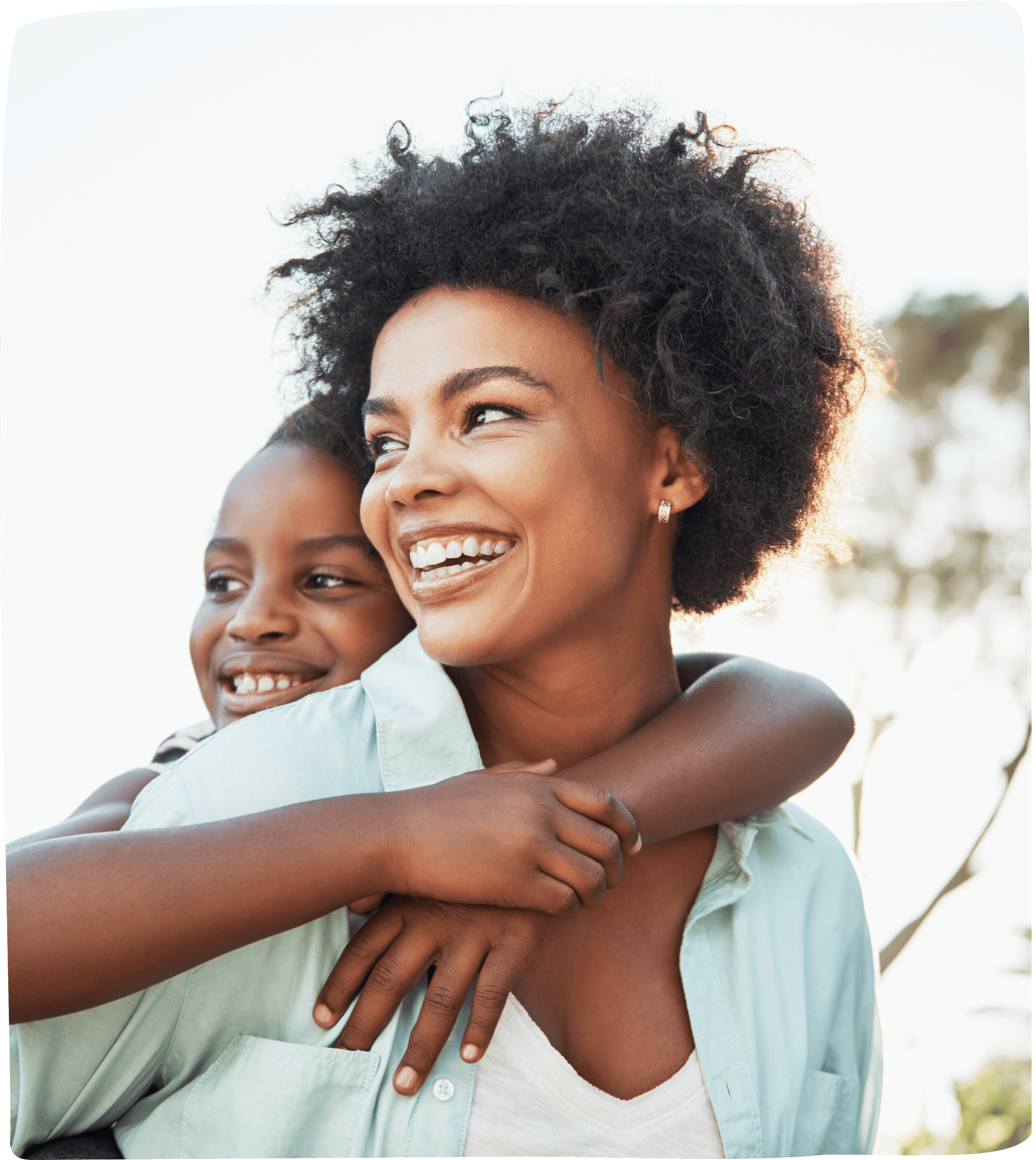 A parent embracing her daughter, both smiling happily