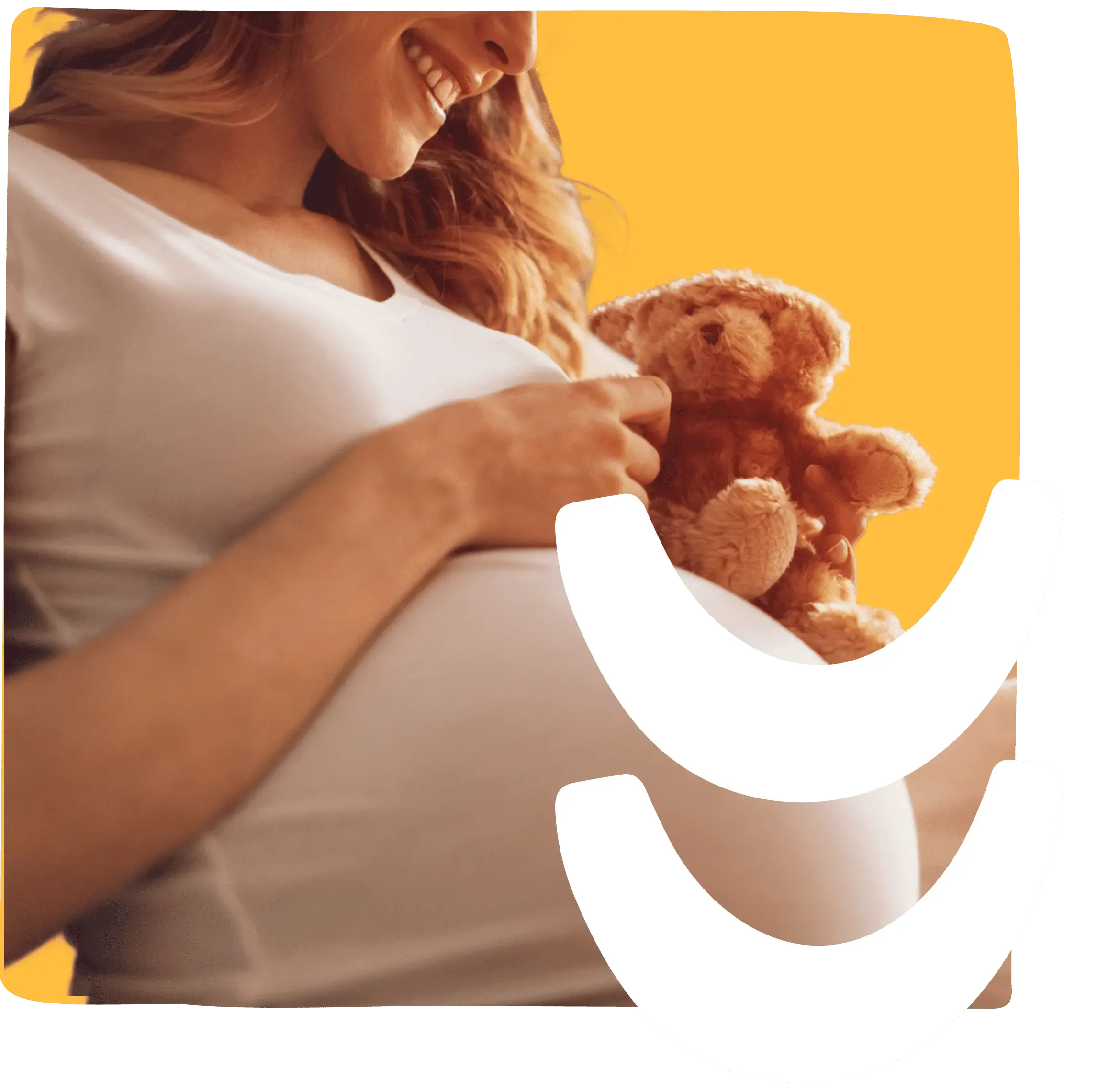 A smiling pregnant woman holding a teddy bear on a yellow background, illustrating pregnancy blood tests.