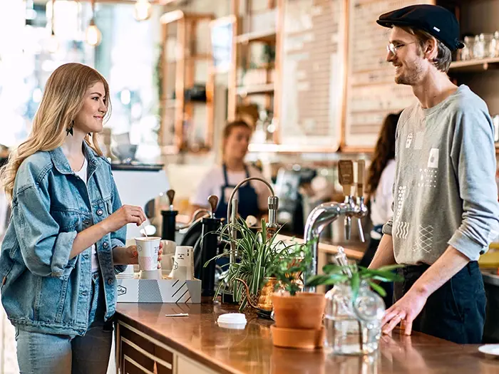 People talking to a barista in a cafe 700x525