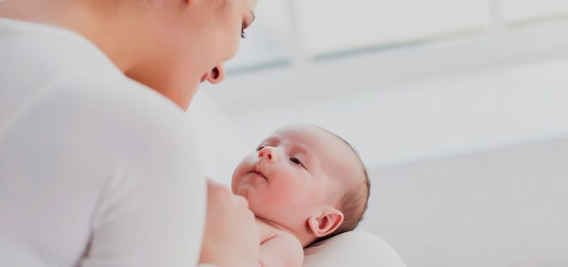 Mãe e bebê sorrindo, com a mãe cheirando o bebê