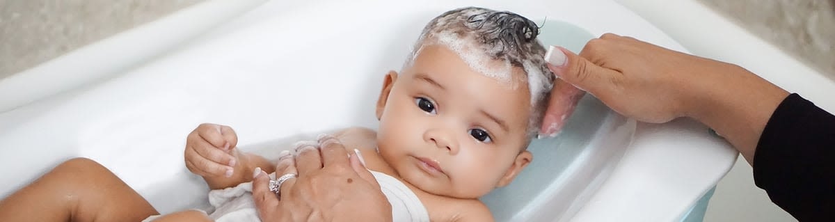 Baby being bathed with gentle lather on head, representing Johnsons Baby care.