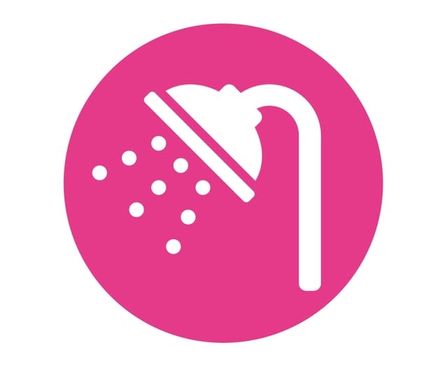 Showerhead spraying water is centered within a pink circle. The water droplets form a scattered pattern beneath the showerhead. The background is entirely pink.