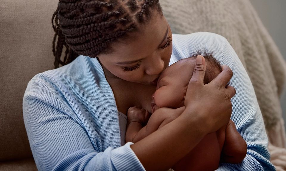 Article card Baby Care Guide, Image of a mother smiling while gently hugging her baby