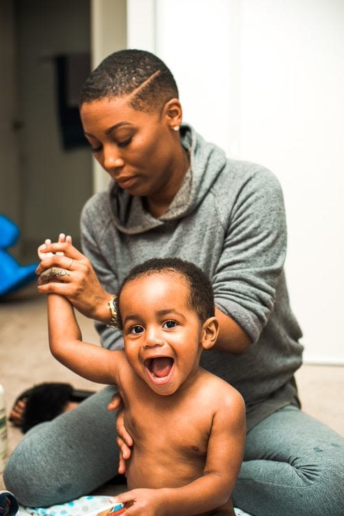 woman moisturizing a baby with body lotion