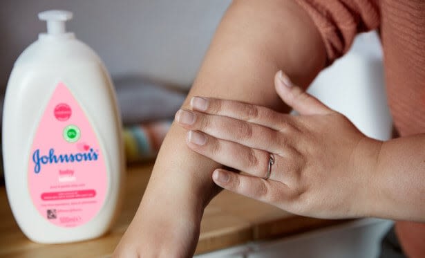 Mulher aplicando Johnson's Baby Loção em suas mãos