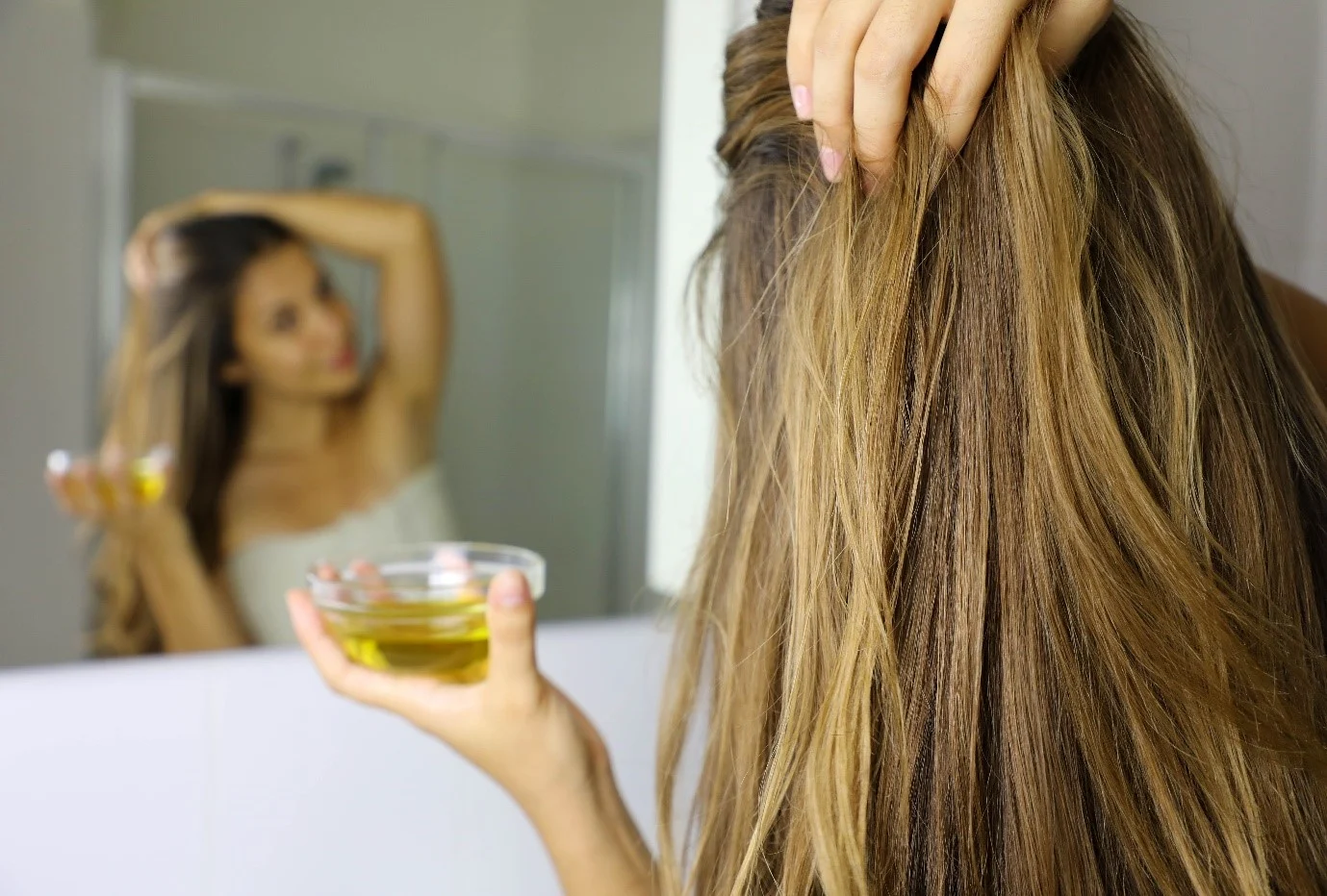 Woman applying Oil to her Hair