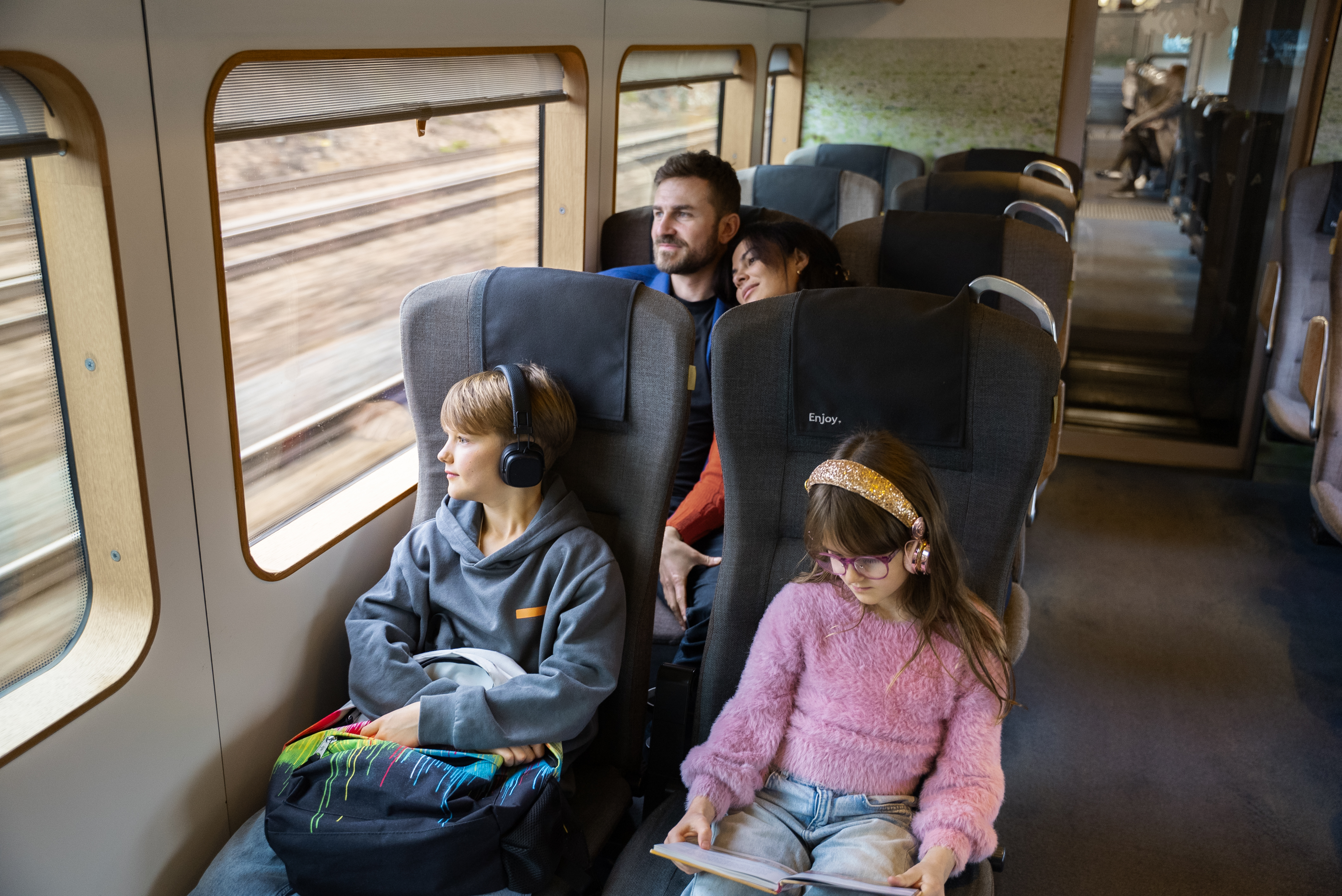 Eine Familie genießt gemeinsam ihre Reise im Arlanda Express, mit hellem, gepflegtem Innenraum und großzügiger Beinfreiheit.