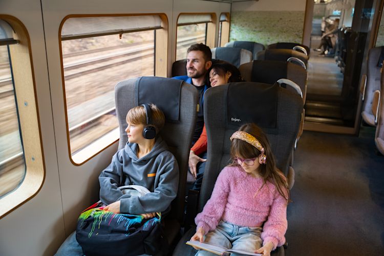 Eine Familie genießt gemeinsam ihre Reise im Arlanda Express, mit hellem, gepflegtem Innenraum und großzügiger Beinfreiheit.