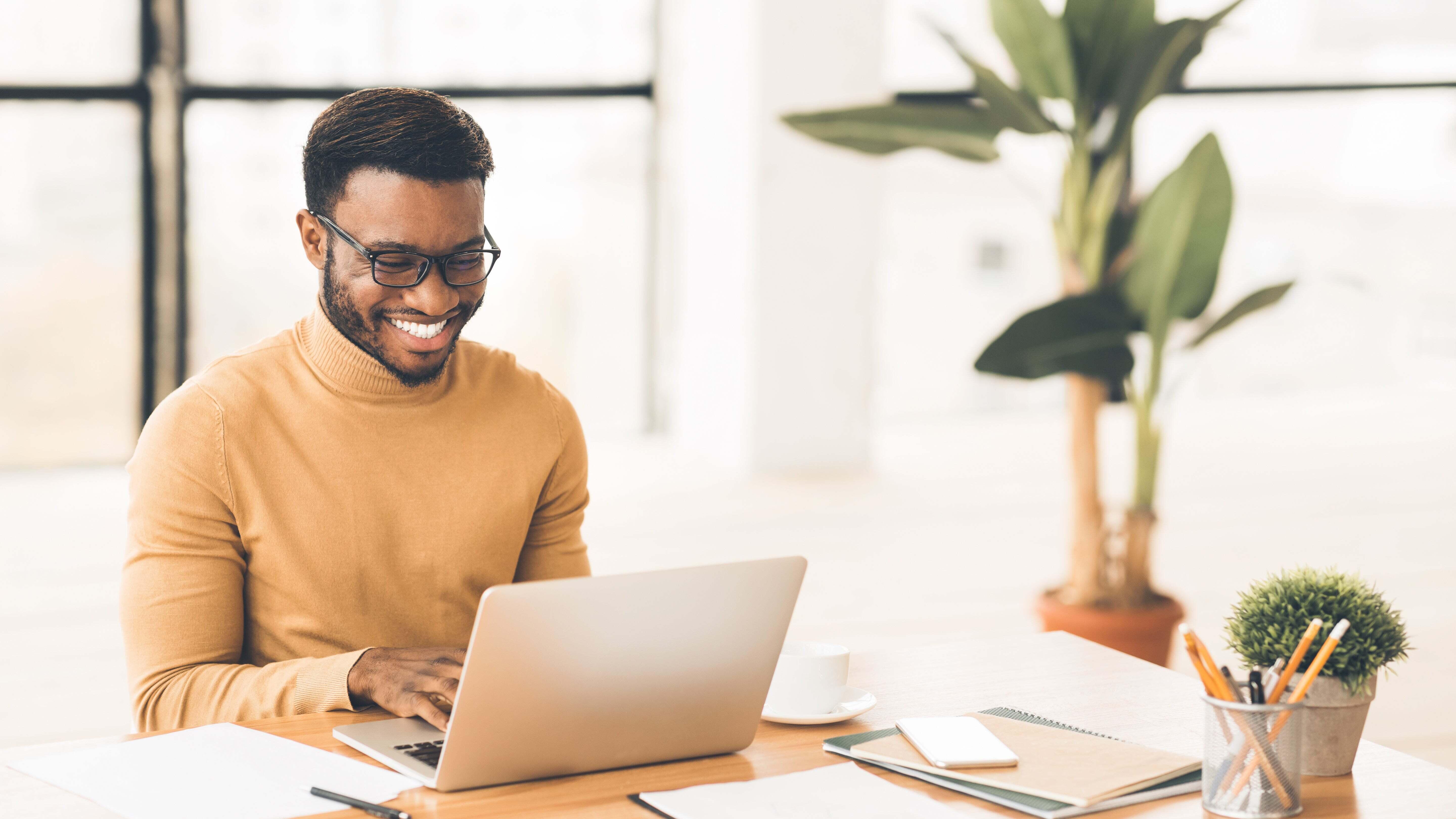 A man smiling while on his laptop