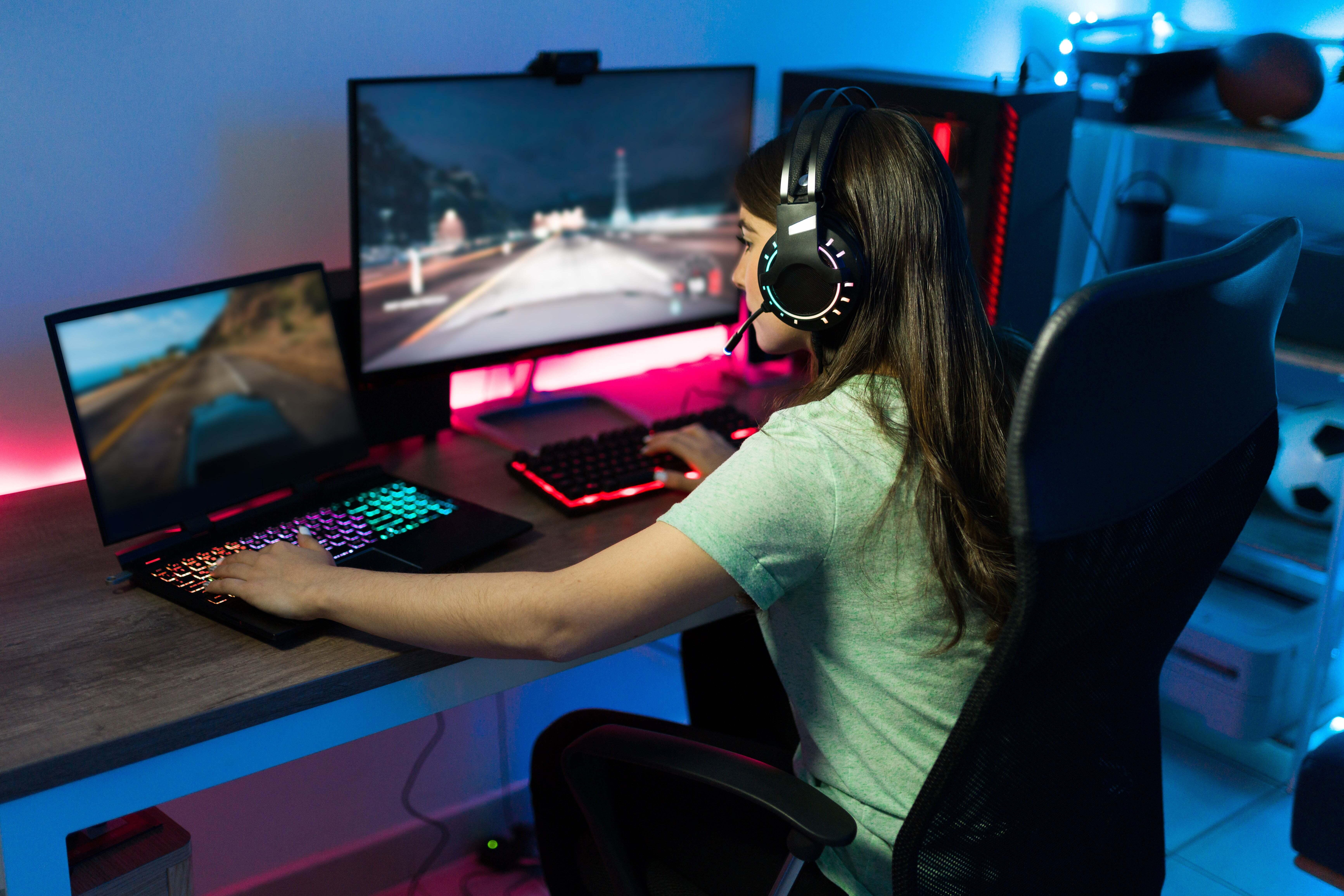 A girl playing on a gaming laptop at her desk