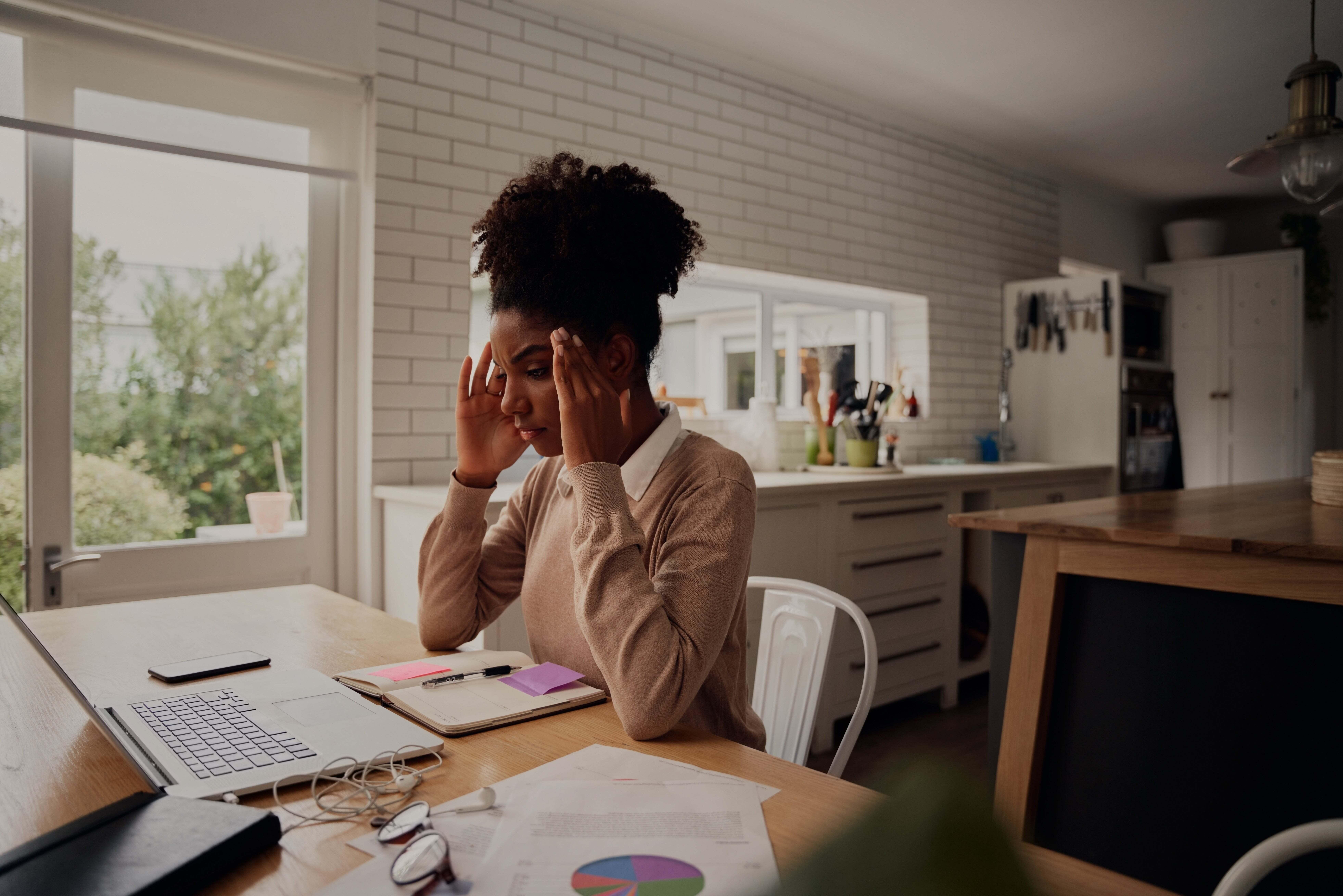 A woman looking indecisive as she stares at her laptop