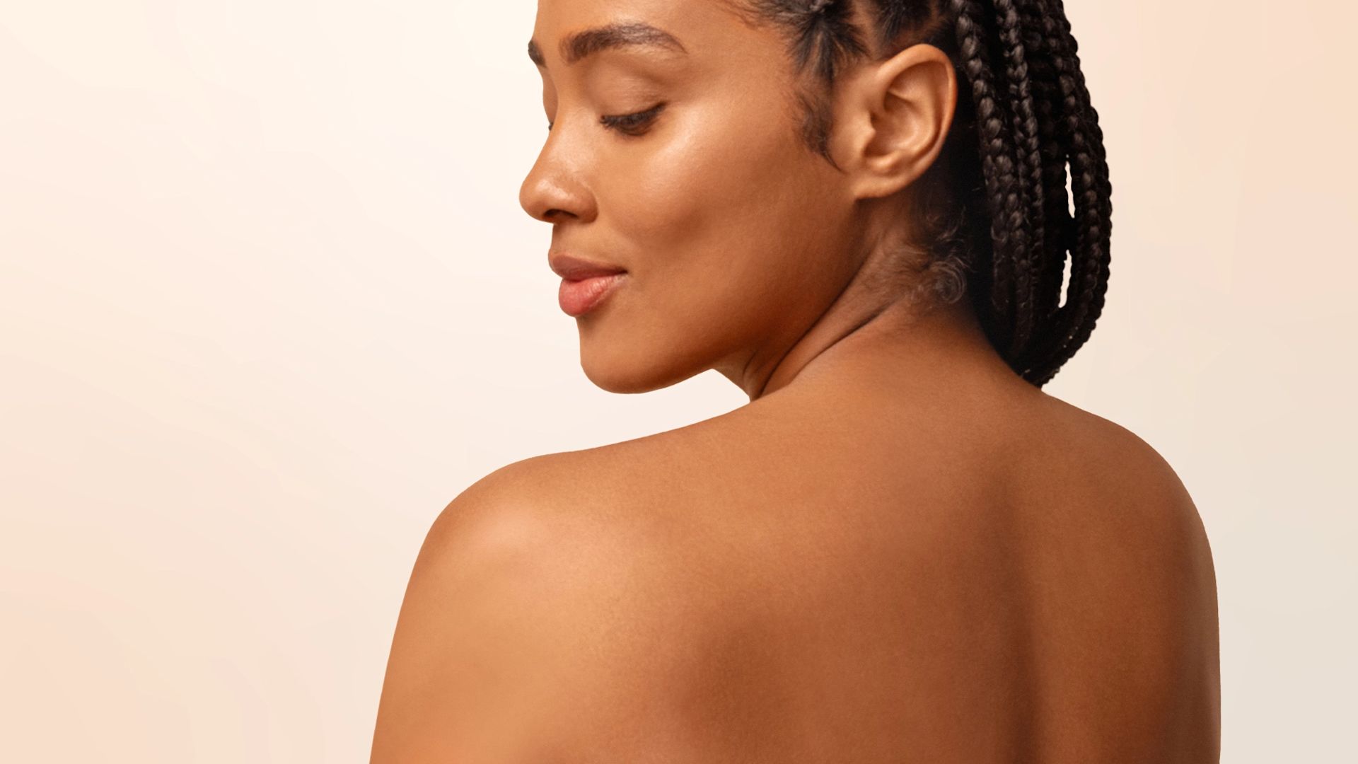 A woman with long braids cascading down her back, showcasing her soft and luminous skin
