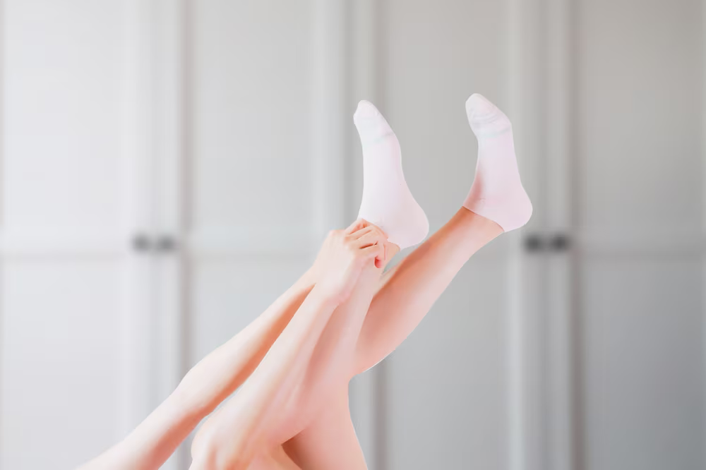 Woman applying moisturizer to her dry, cracked feet.