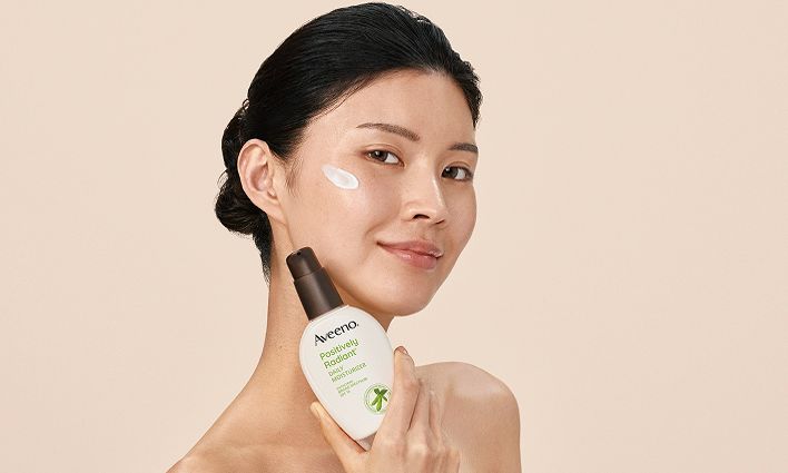 Woman with cream on her face, featuring Aveeno® Positively Radiant® Antioxidant Brightening Power