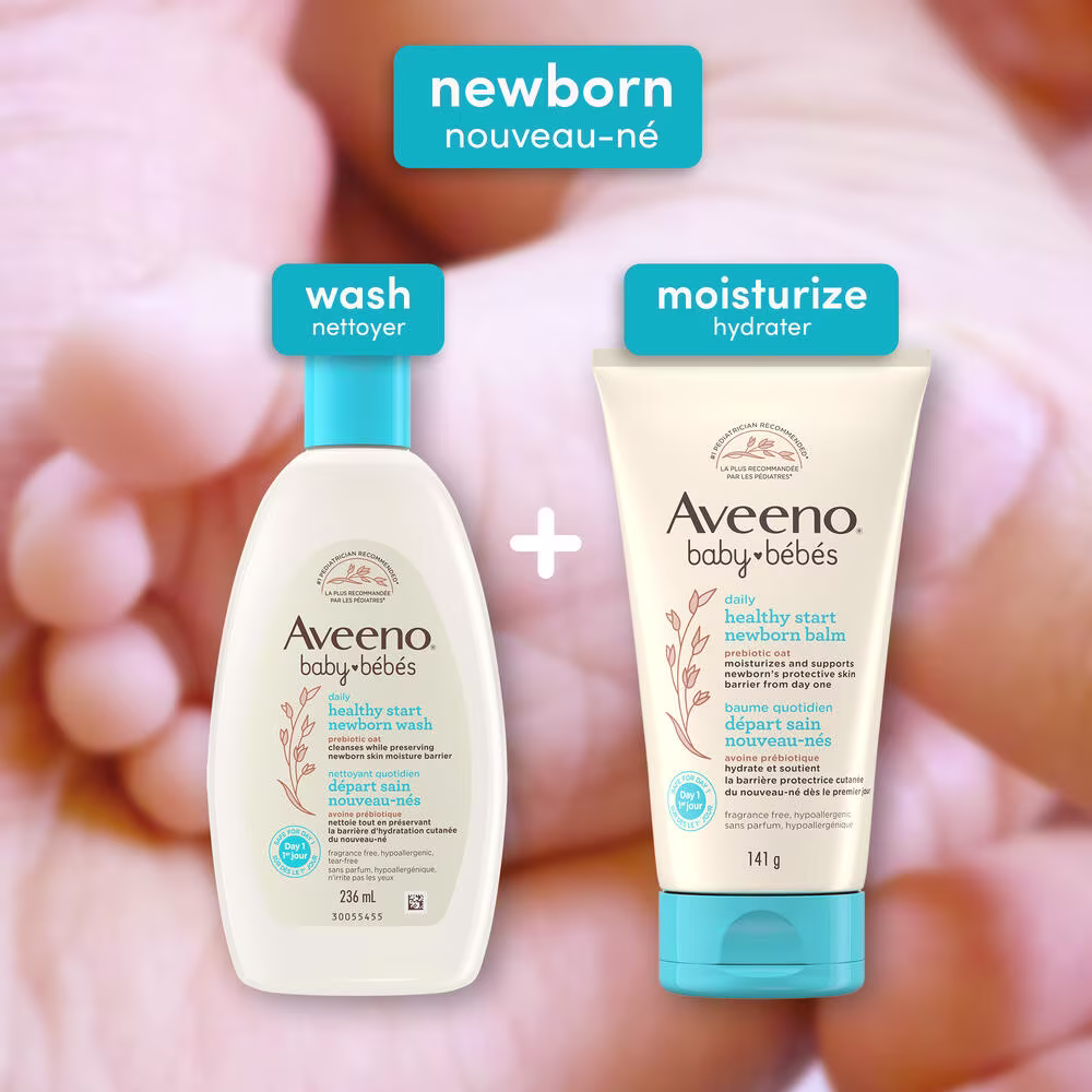 Front shot of Aveeno® Baby Healthy Start Newborn Wash and Balm products and close-up of baby's foot in parent's palm in the background