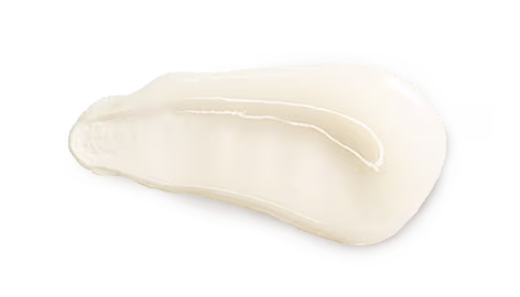 Shiny off white lotion on a white surface showcasing a light creamy texture