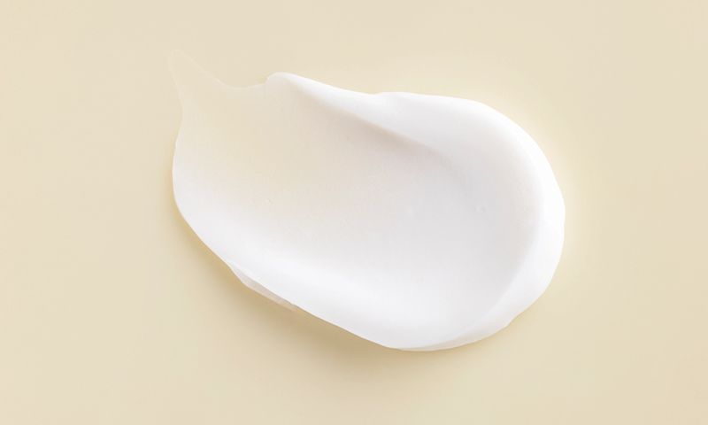 A delicate white cream positioned on a white surface showcasing its soft texture and uniform color
