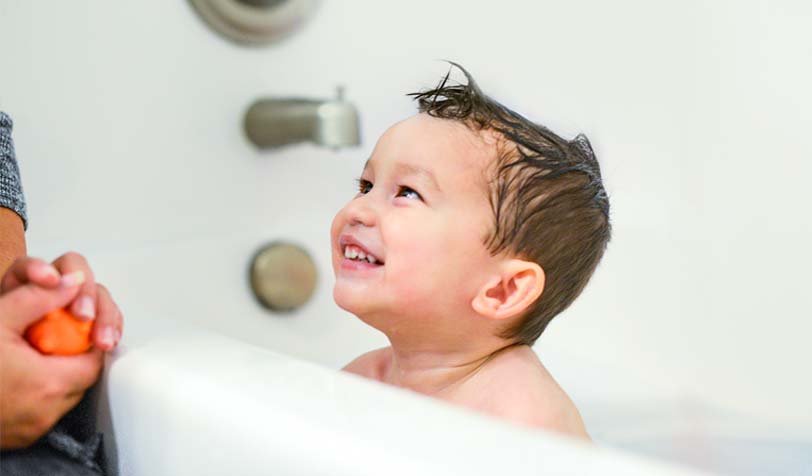 Image focusing a baby during bath time, highlighting a mother and baby happy moment