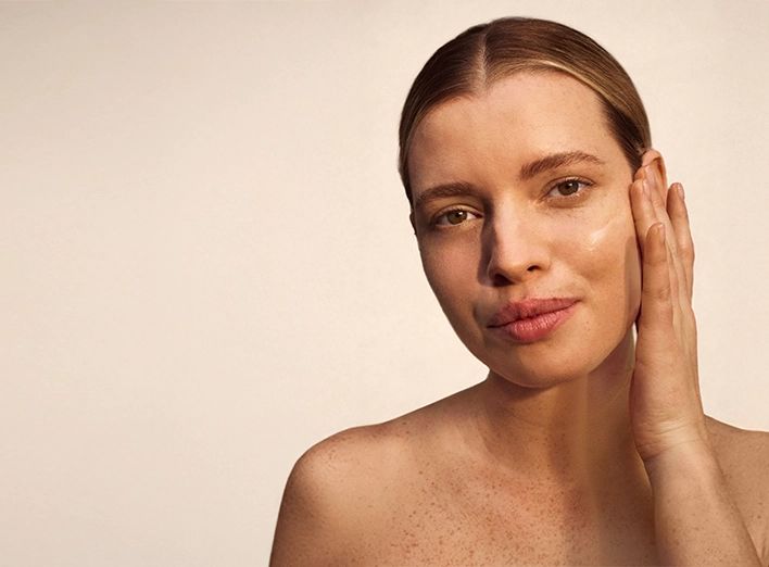 Woman with freckles on her face, smiling softly, showcasing her natural beauty and warm expression