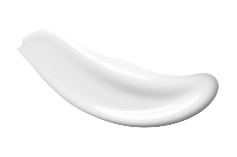 Shiny white lotion on a white surface showcasing its lightweight texture and uniform color
