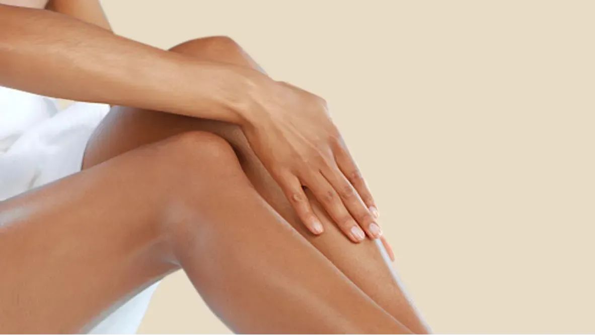 A woman gently touching her legs which appear to be moisturized
